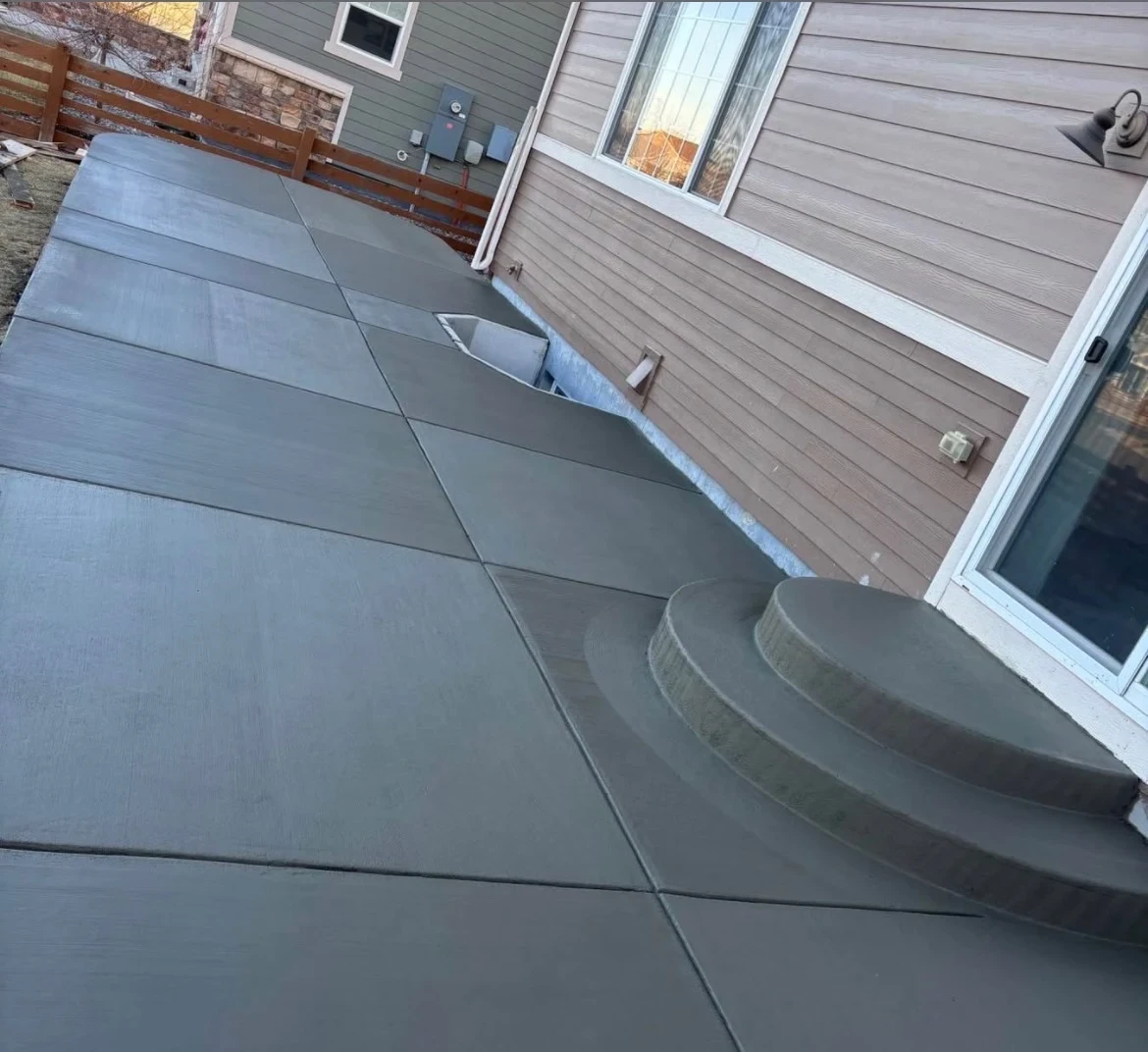 Concrete patio beside a Bethesda home with smooth square slabs and steps leading to a sliding glass door.